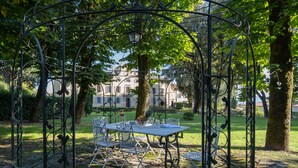 Un jardín con un pabellón de metal, una mesa y sillas.