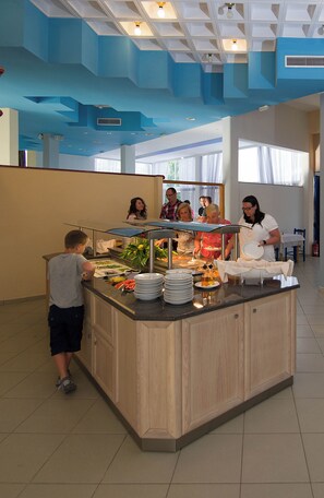 Een buffetgedeelte met een centraal eiland, diverse gerechten en een groep mensen.