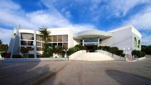 Ein modernes Gebäude mit einer gewölbten Fassade, großen Fenstern und einem zentralen Eingang mit Stufen.