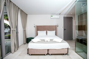 A modern hotel room with a large bed, a glass shower enclosure, and a view of the outdoors. - Happy Days (Rhodes)