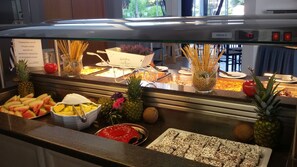 Een buffet met diverse gerechten, waaronder fruit, groenten en desserts.