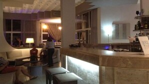 A modern hotel lobby with a bar area, seating arrangements, and a visible staircase. - Happy Days (Rhodes)