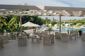 Et udendørs opholdsområde med træmøbler og en pool i baggrunden.