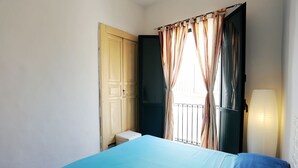 A bedroom with a bed, a wardrobe, a window with curtains, and a bedside lamp. - Casa Marinella (Scicli)