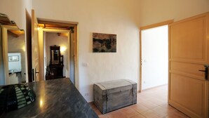 A room with a wooden chest, a painting on the wall, and a door. - Casa Marinella (Scicli)