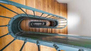 A spiral staircase with a wooden finish and metal handrails. - LV Premier Bica- BI (Lisbon)