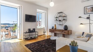 A spacious living room with a large window, a flat-screen TV, a wooden coffee table, and a white sofa. - LV Premier Bica- BI (Lisbon)