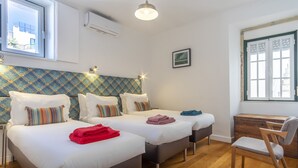 A hotel room with two beds, a wooden desk, a chair, and a window with a view. - LV Premier Bica- BI (Lisbon)