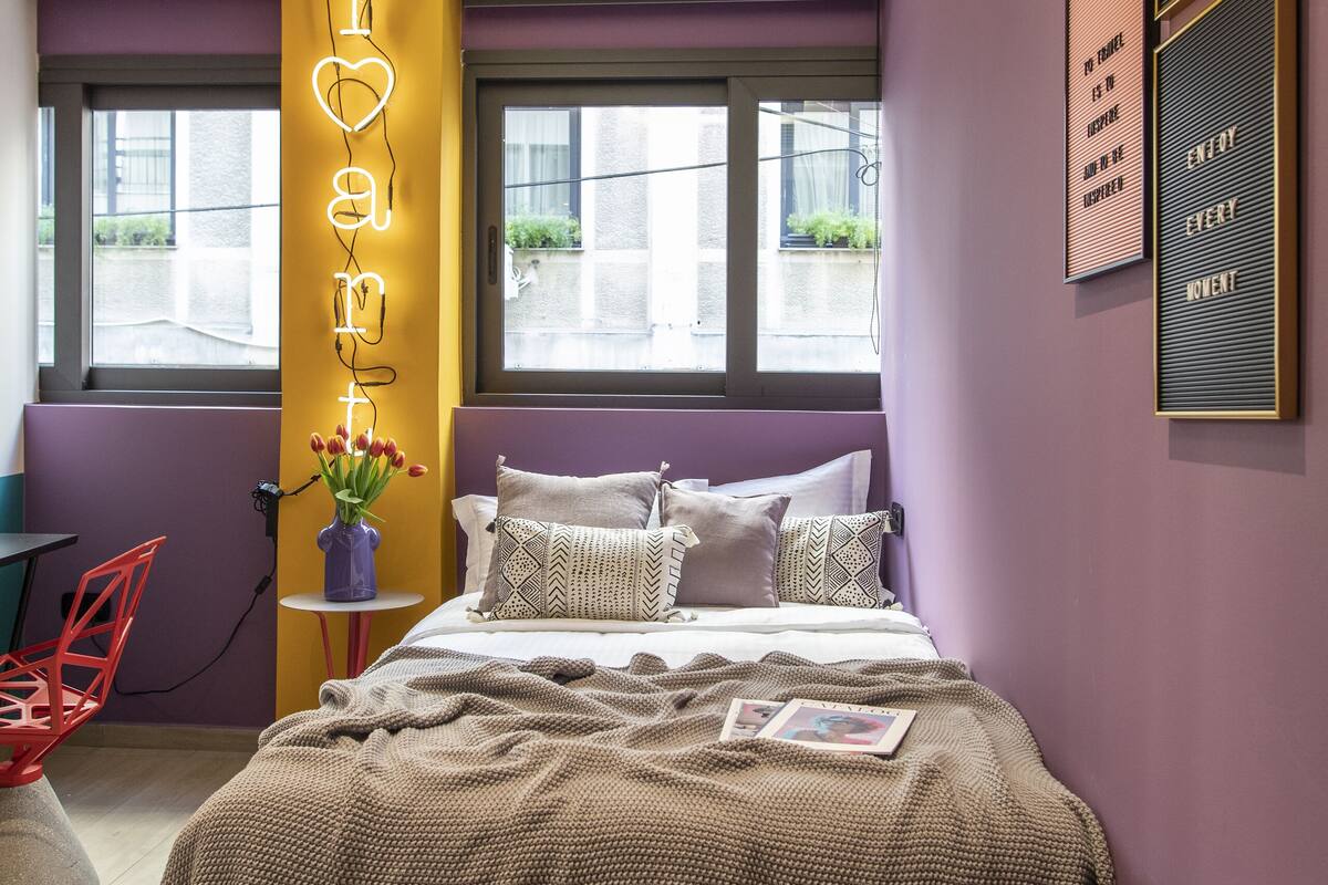 A modern bedroom with a bed, bedside table, and a window.