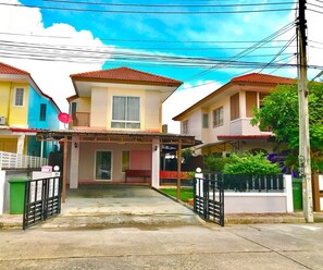 A residential street with houses featuring red-tiled roofs and a central entrance gate. - Little Tokyo House (Si Racha)