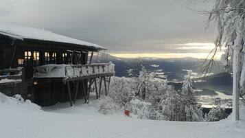 Un lodge en la montaña cubierto de nieve con un balcón que domina un valle.