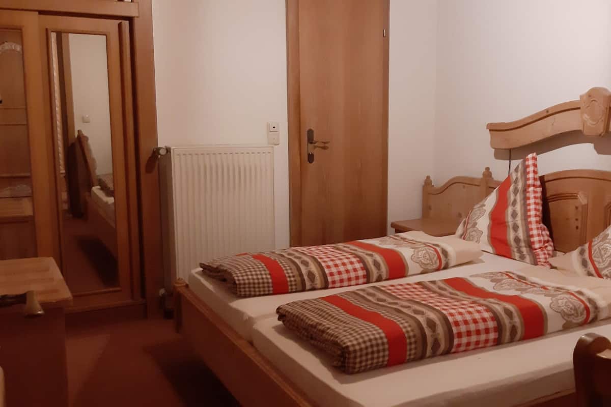 Een slaapkamer met twee bedden, houten hoofdeinden en ruitjes beddengoed.