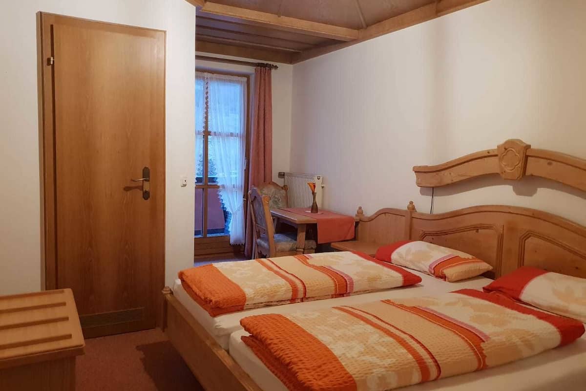 Een slaapkamer met twee bedden, een houten deur, een bureau en een raam met gordijnen.