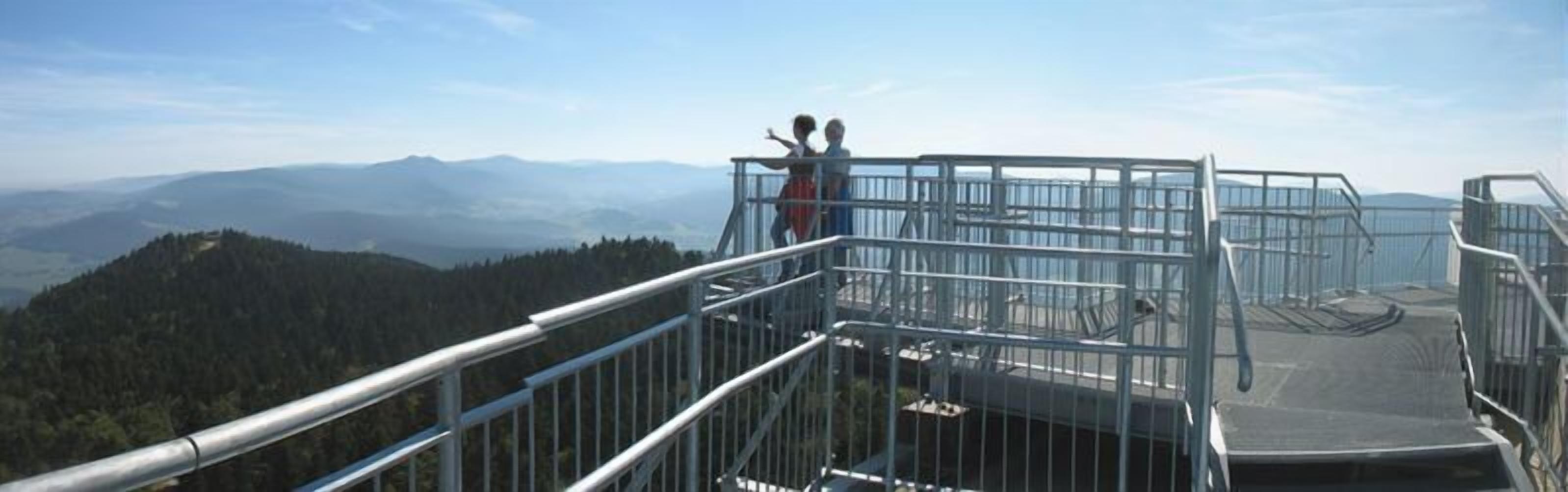 A metal observation platform with railings overlooking a mountainous landscape.
