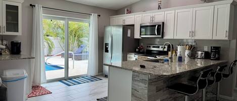 Una cocina moderna con armarios blancos, una isla central, un microondas y un refrigerador.