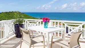Ein Balkon mit einem weißen Tisch und Stühlen, einem Blumentopf und einem Blumenstrauß.