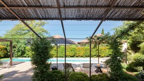 Un patio couvert avec une piscine, des chaises longues et une table où sont servis des boissons.