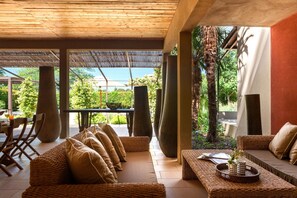 A spacious outdoor seating area with wicker furniture and a view of lush greenery.