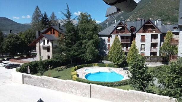 A hotel with a swimming pool surrounded by trees and a mountain backdrop. -  4 LIRONES - THE 4 SLEEPYHEAD DORMOUSES  (Benasque)