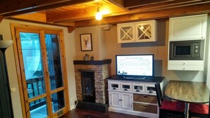 A cozy living room with a stone fireplace, wooden flooring, a television, and a white cabinet with drawers. -  4 LIRONES - THE 4 SLEEPYHEAD DORMOUSES  (Benasque)