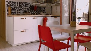 A modern kitchen with white cabinets, a black and white patterned backsplash, and red chairs. - Pisani 32 at the Marina (Cagliari)
