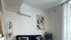 A modern living room with a dark blue sofa, a wooden coffee table, and a painting on the wall. - Pisani 32 at the Marina (Cagliari)