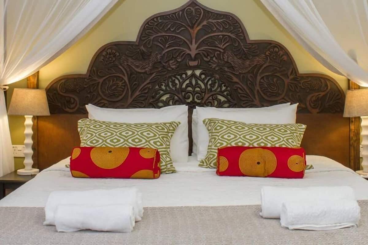 A bed with a canopy, decorative headboard, and patterned pillows.