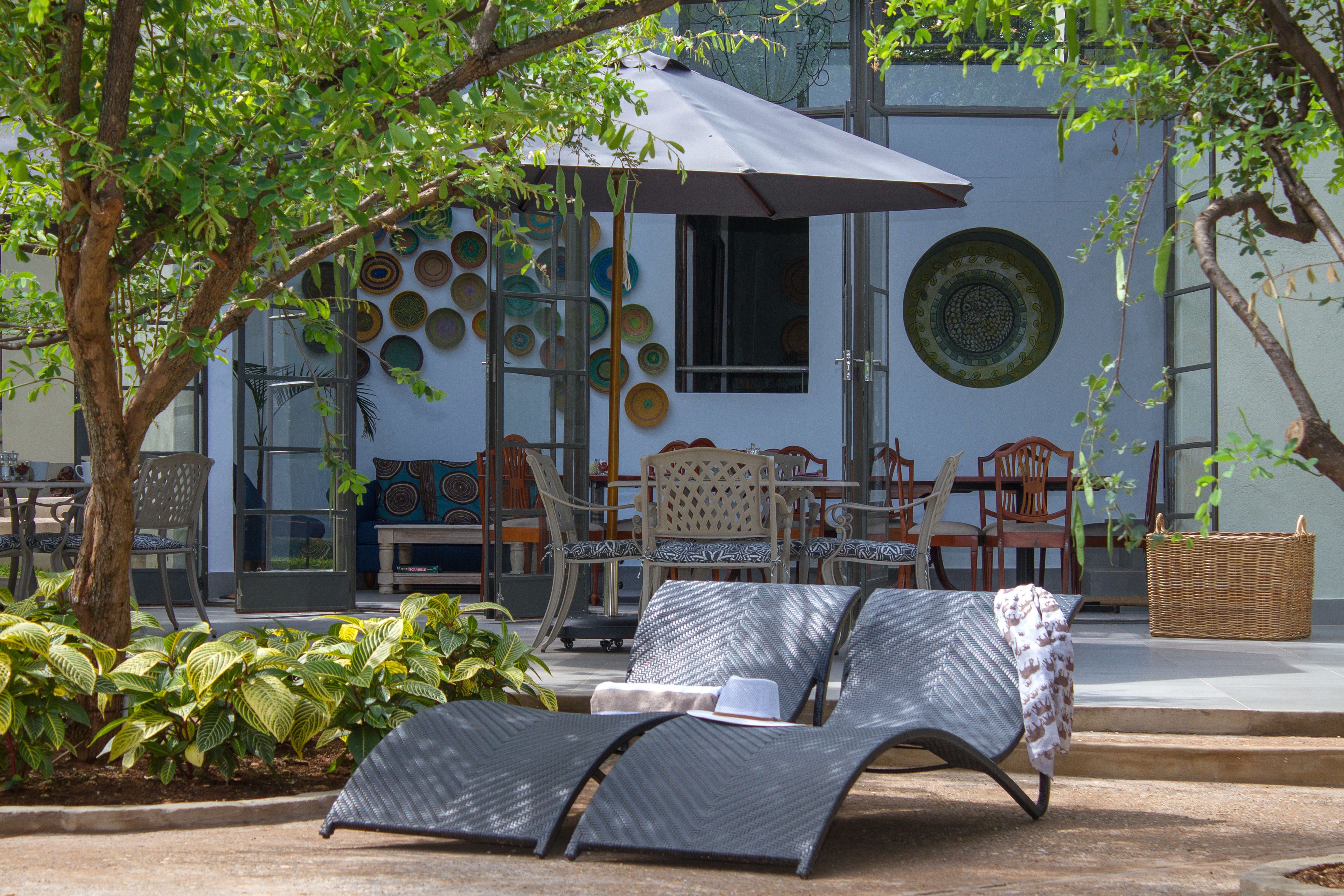 A patio area with lounge chairs, a table, and a large umbrella providing shade.