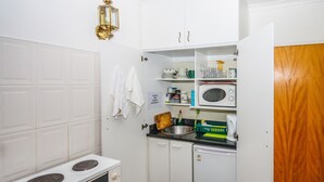 A compact kitchen with a stove, microwave, and cabinets. - Wilmot Cottages (Gqeberha (Port Elizabeth))