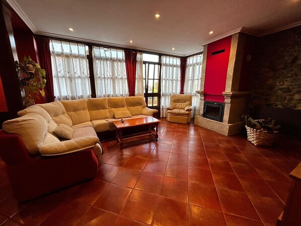 A living room with a sectional sofa, a single armchair, a wooden coffee table, and a fireplace. - Casa El Pontón for 8 people (Llanes)