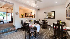 A dining area with tables set for four, chairs, and a ceiling fan.
