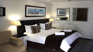 A hotel room with a large bed, two bedside lamps, a ceiling fan, and framed pictures on the walls.