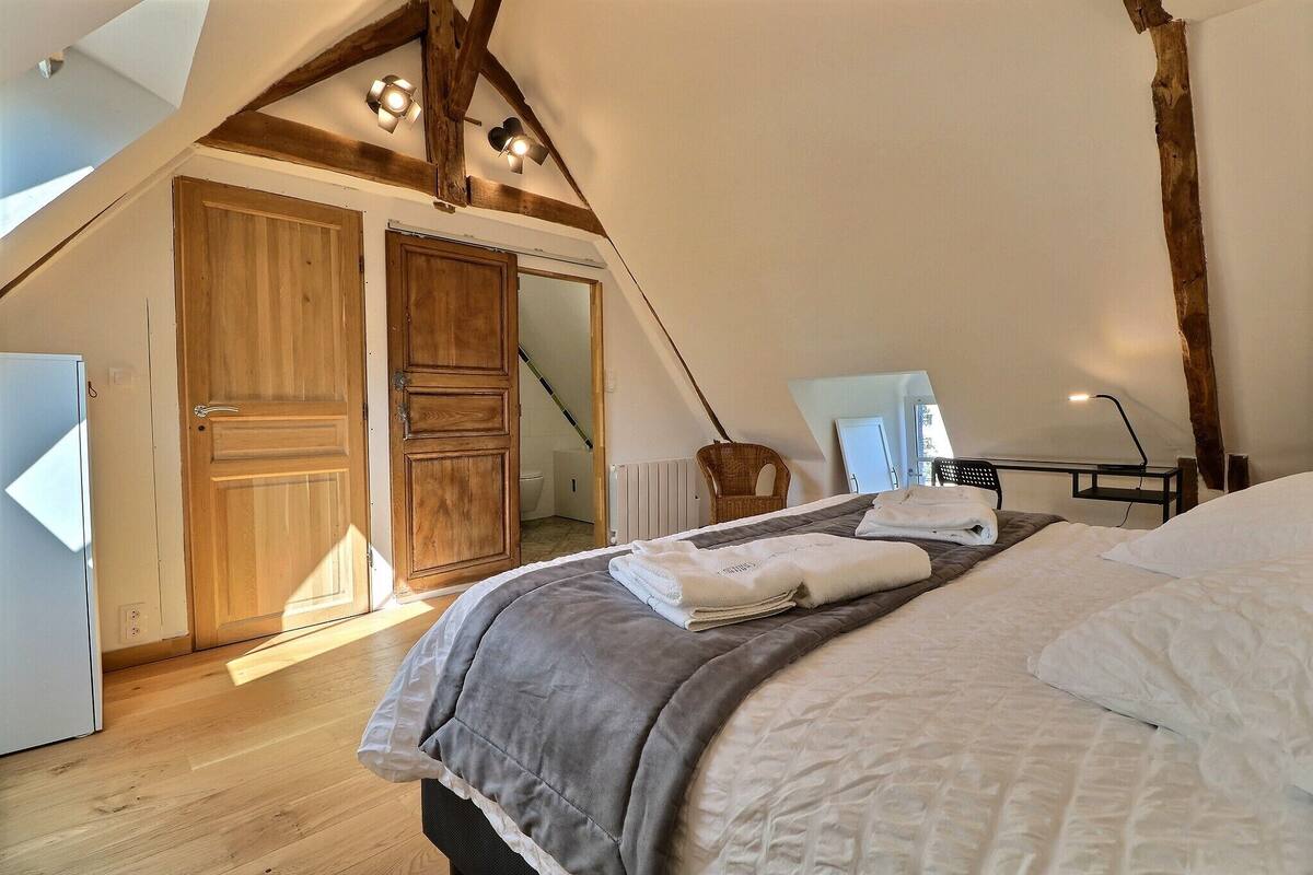 A bedroom with a large bed, wooden wardrobe, and a view of the outside.