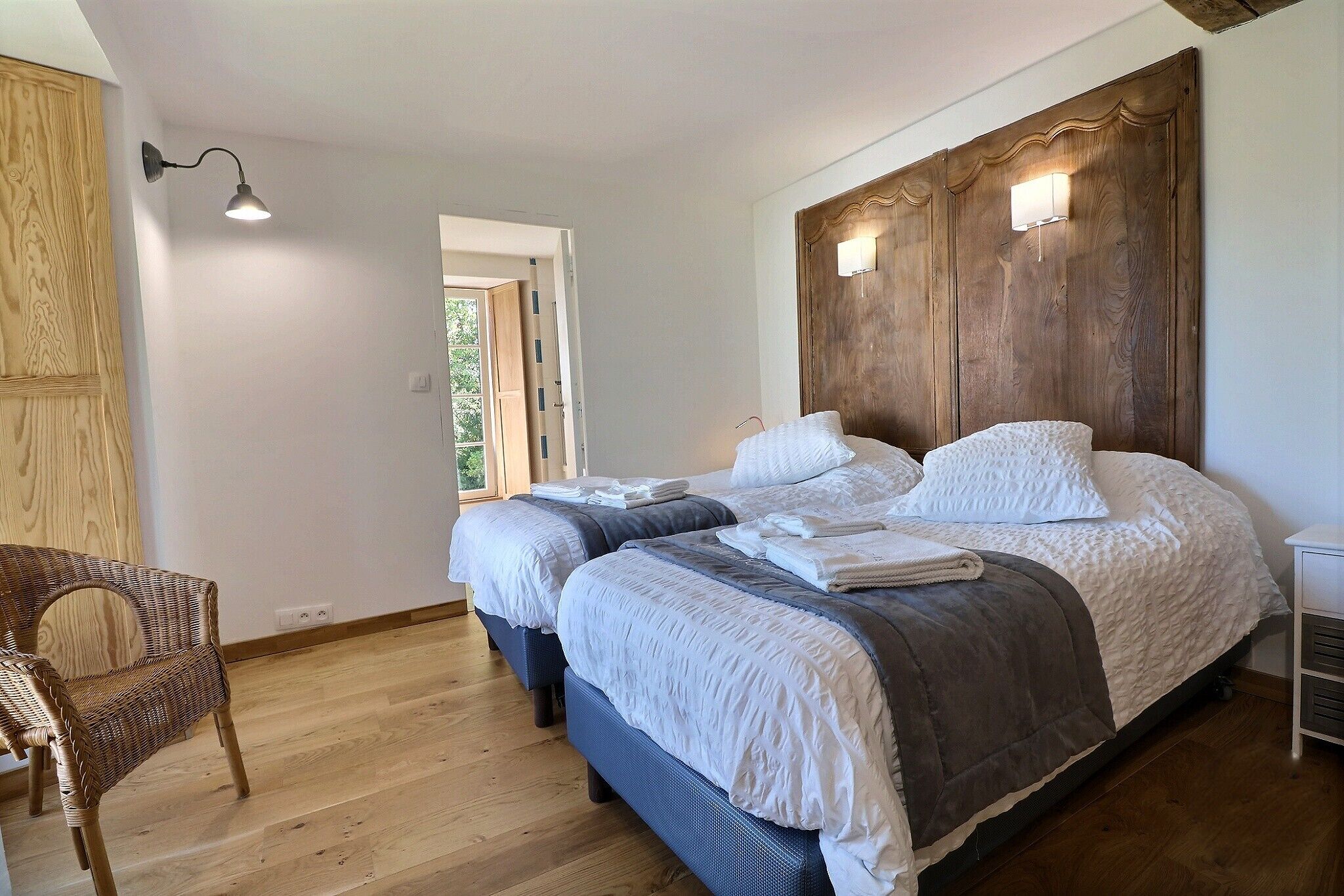 Un dormitorio con dos camas, un armario de madera, una silla y una mesita de noche.