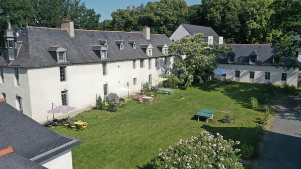 A courtyard with a green lawn, outdoor seating, and a tennis table. - Chateau des Fontenelles (Chavagne)