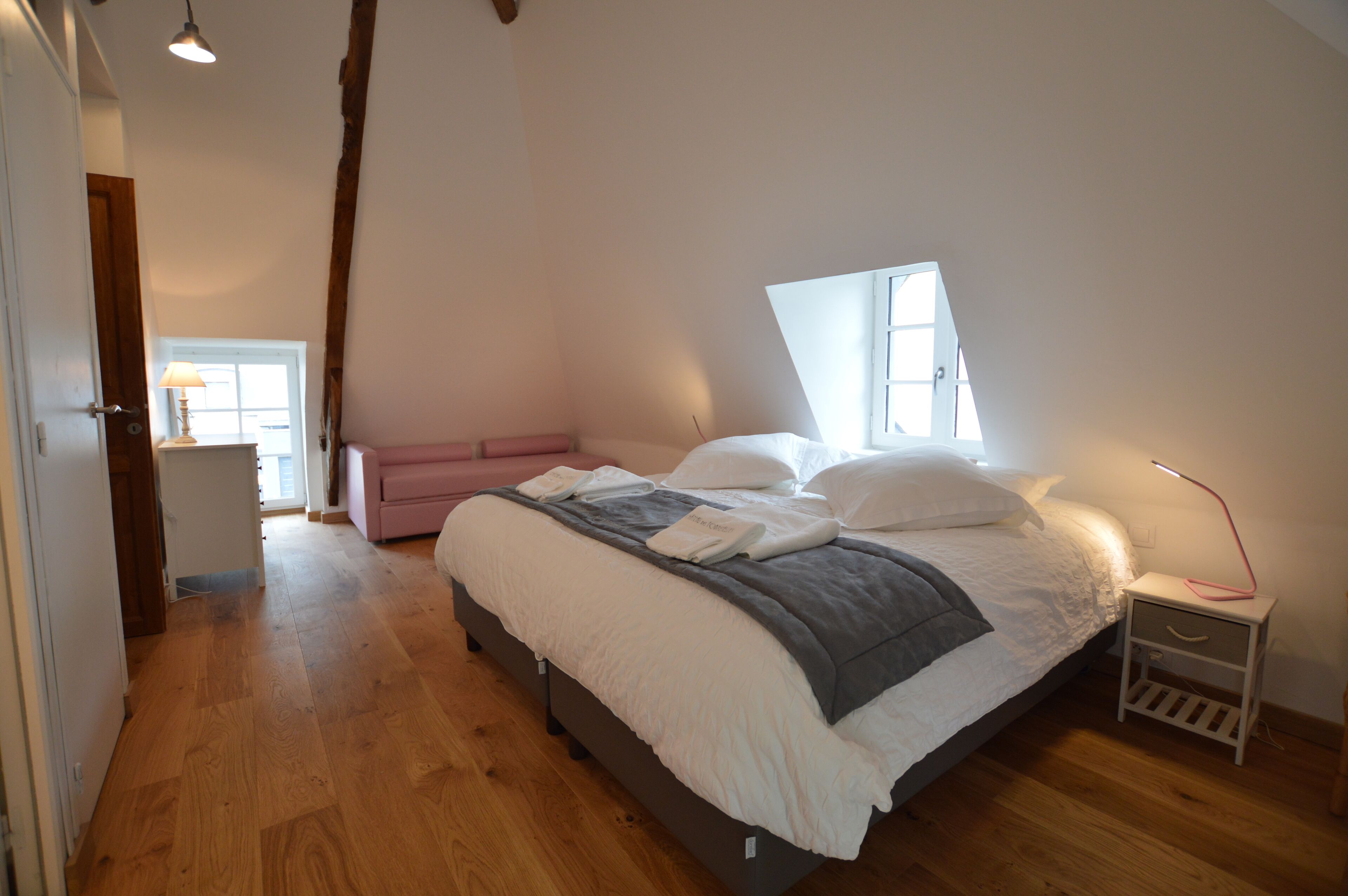 A bedroom with a bed, bedside table, and a window.