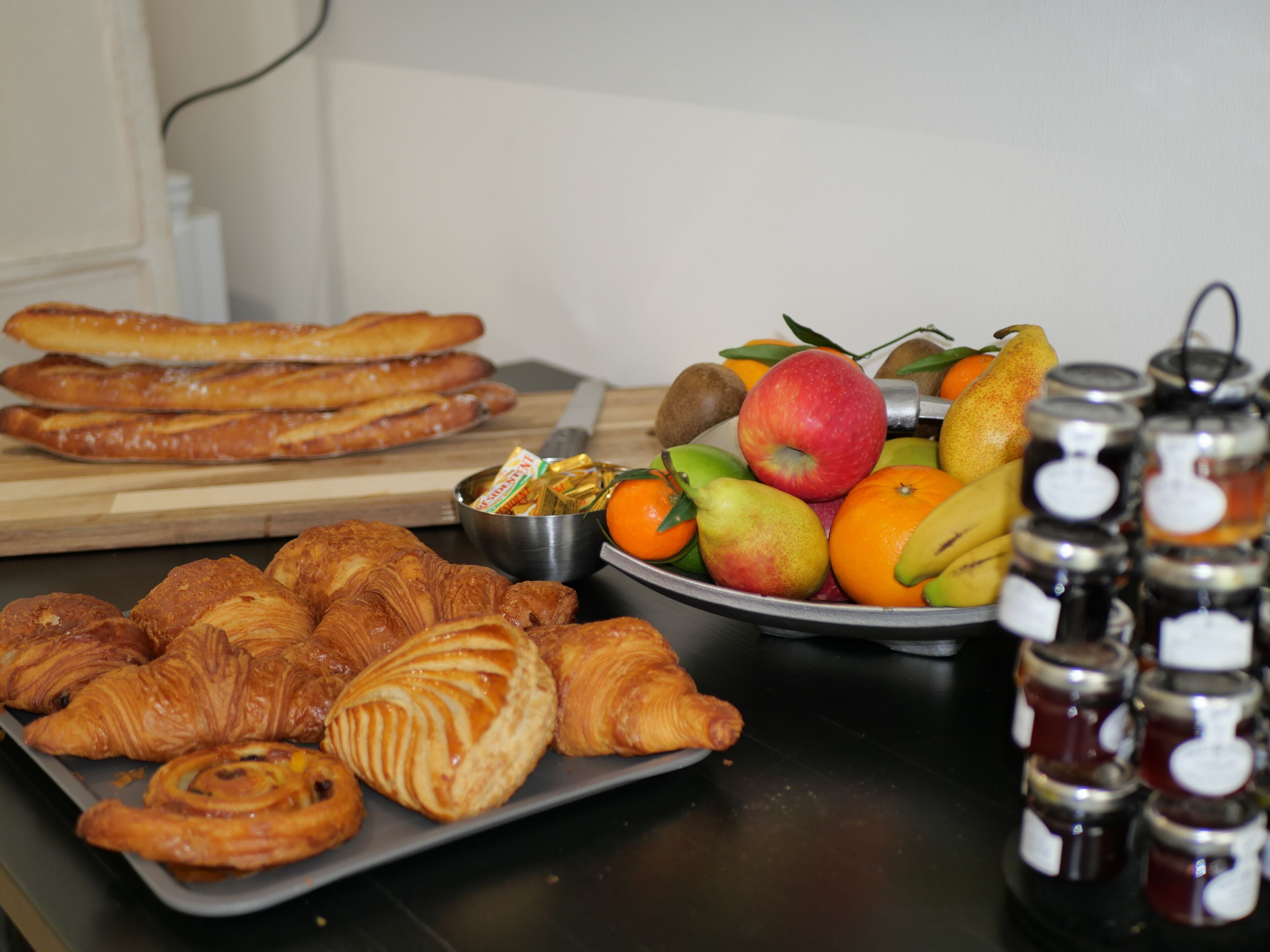 Ein Esstisch mit Gebäck, Früchten und Marmeladengläsern.
