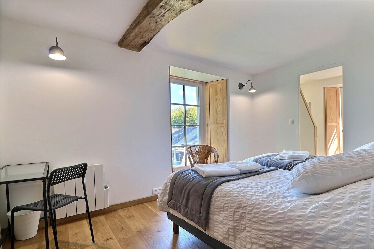 A bedroom with a bed, a chair, a desk, and a window.