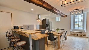 Una cocina moderna con una isla central, taburetes de bar y un comedor con mesa y sillas.
