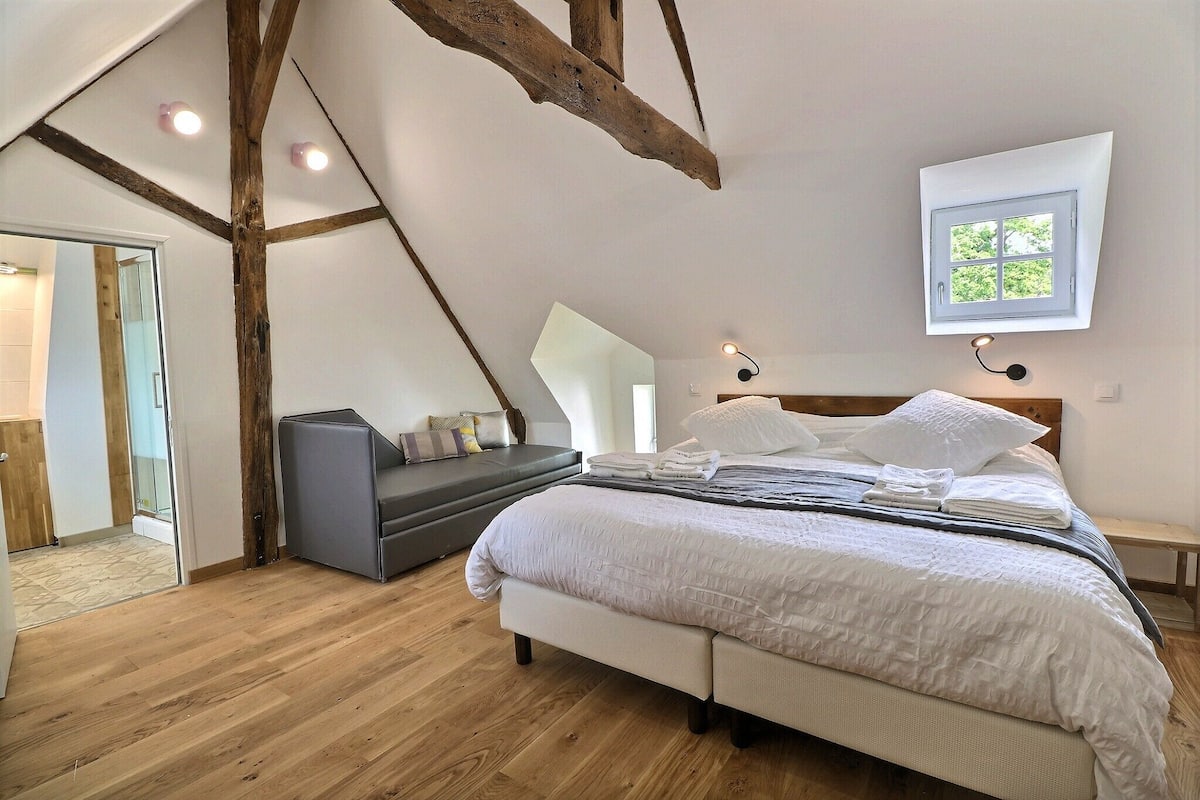 A bedroom with a bed, bedside table, and a window.