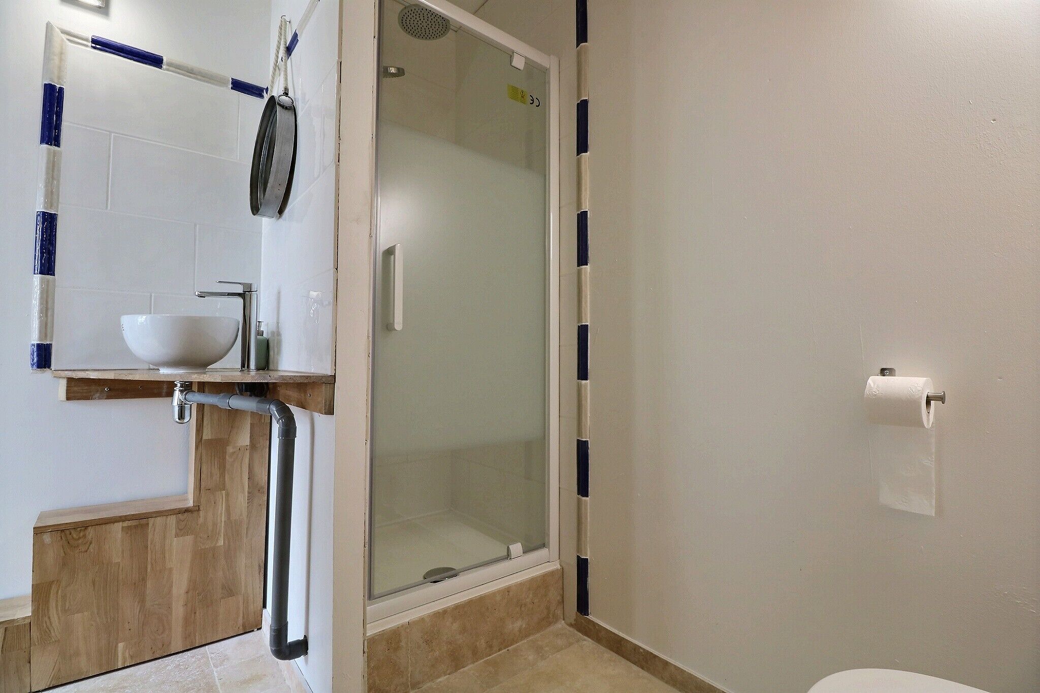 A bathroom with a glass shower enclosure, a white sink, and a toilet.