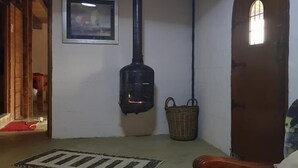 A room with a fireplace, a wooden door, a framed picture on the wall, and a patterned rug on the floor. - The Hay Barn (Lions River)