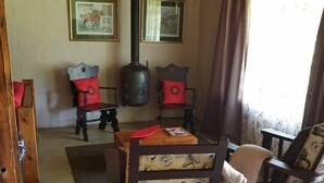A cozy room with a wooden table, chairs, a fireplace, and framed pictures on the wall. - The Hay Barn (Lions River)