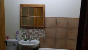 A bathroom with a toilet, sink, and bathtub. - The Hay Barn (Lions River)