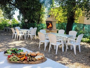 Un espace extérieur aménagé pour les repas, avec un foyer et une table dressée.