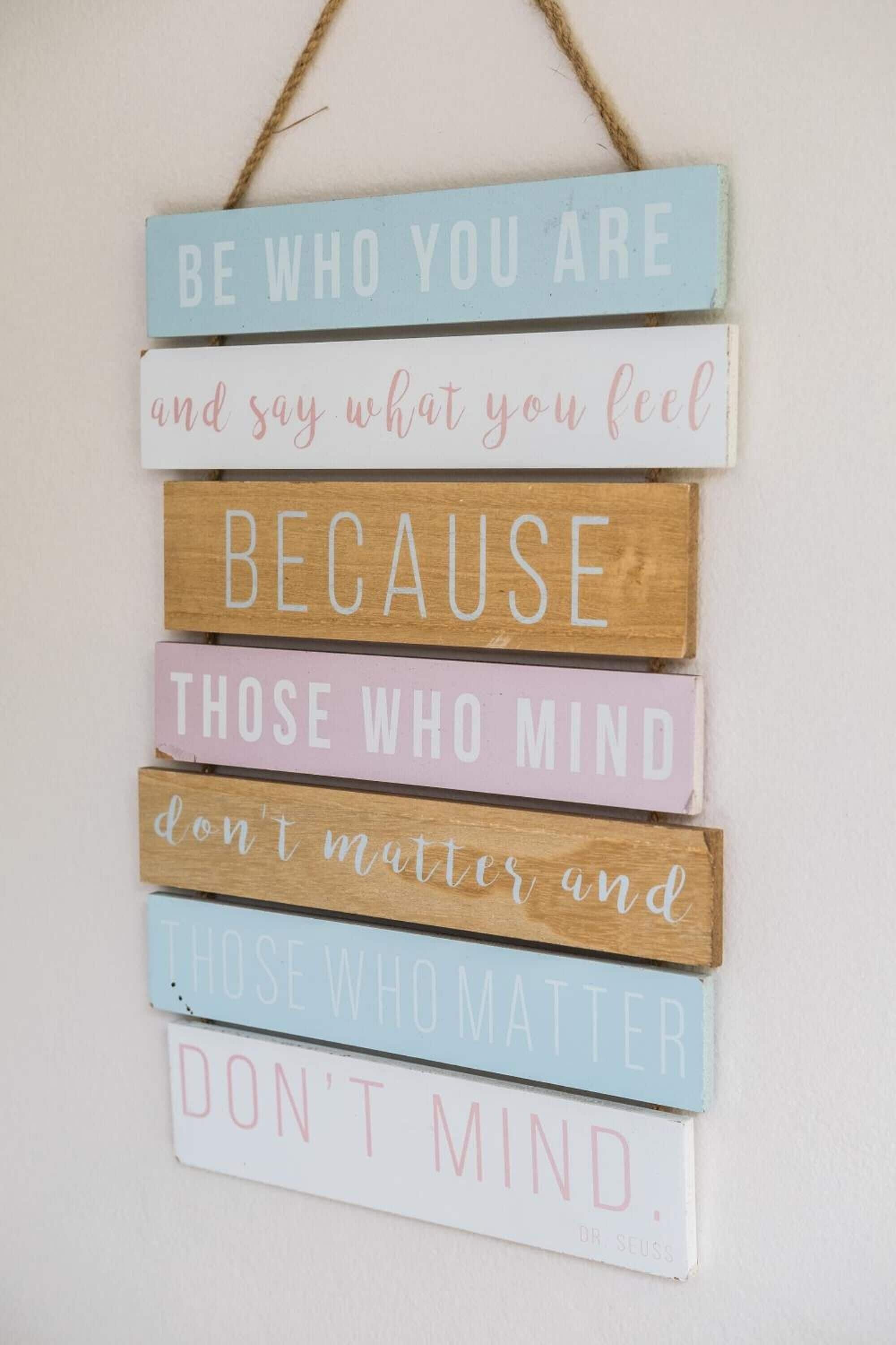A motivational quote on a wooden sign hanging on a wall.