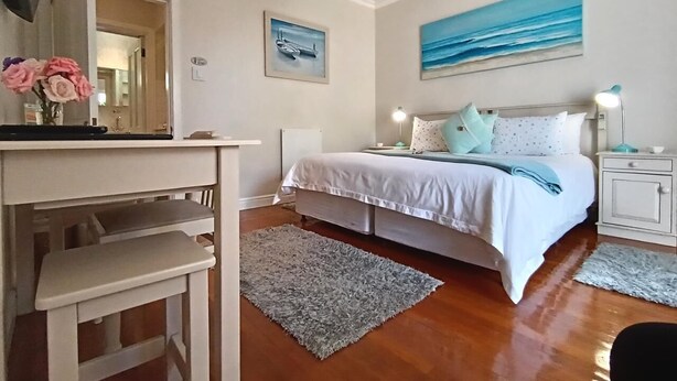 A bedroom with a bed, bedside tables, a desk, and a mirror. - On The Bay B&B (Gqeberha (Port Elizabeth))