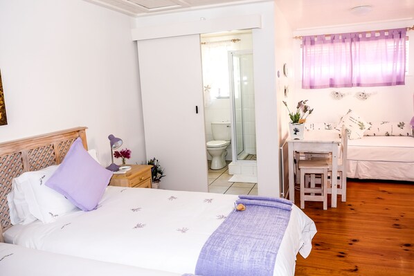 Un dormitorio con cama, mesita de noche, escritorio y zona de ducha.