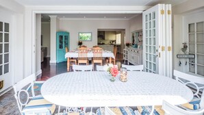 A dining area with a round table, chairs, and a kitchen in the background. - On The Bay B&B (Gqeberha (Port Elizabeth))