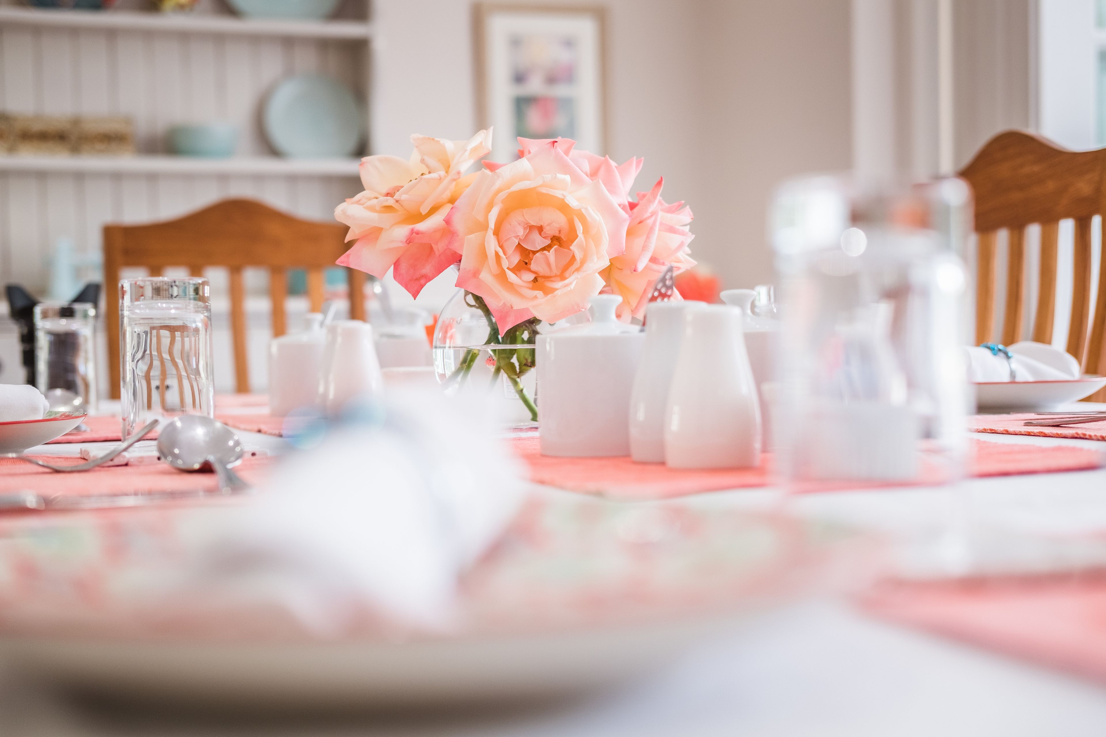 A dining table with pink roses, salt and pepper shakers, and a glass of water.